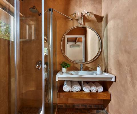 Marni Hotel Premium Studio bathroom with round mirror, walk-in shower and rolled white towels